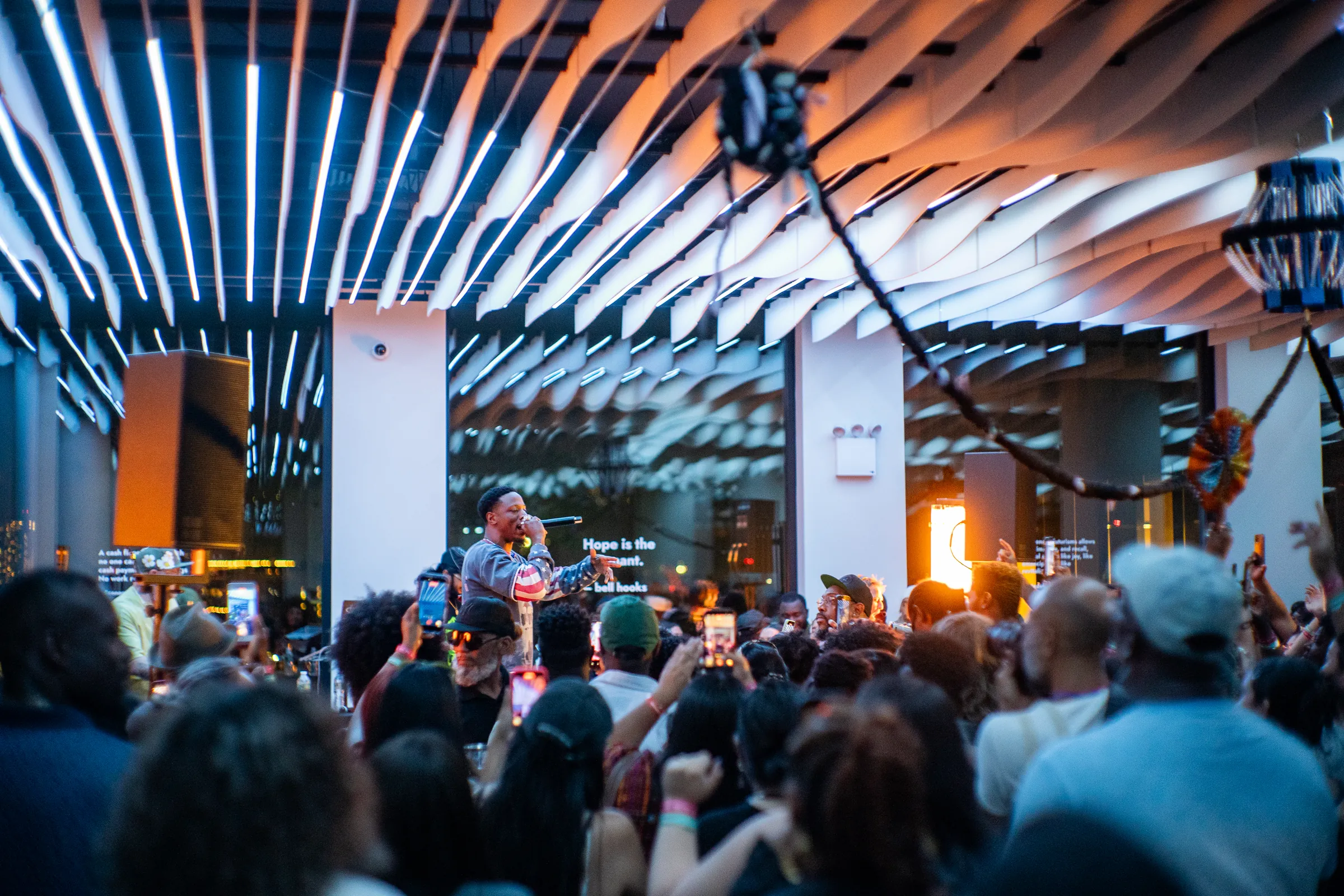 Packed crowd at a nighttime concert under the lit wave ceiling at VESPER, a Brooklyn event venue