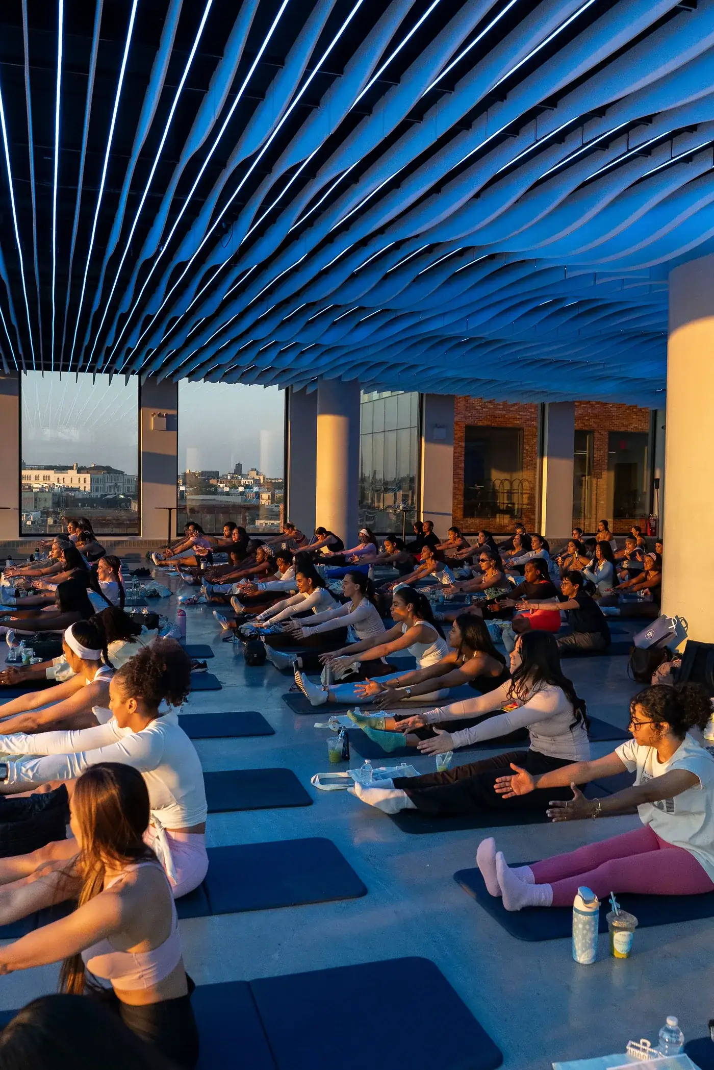 A full wellness class stretching in the evening light at VESPER on the Williamsburg waterfront in Brooklyn