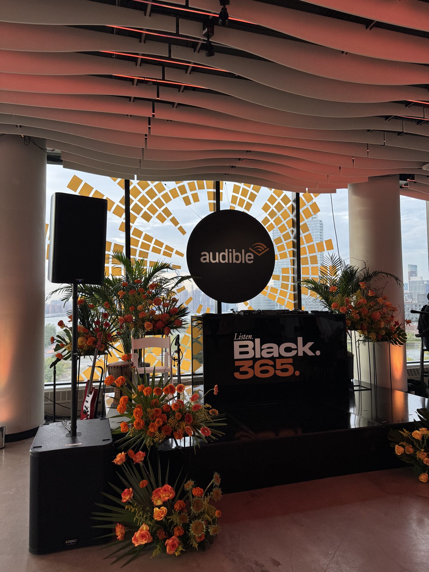 The stage at VESPER for a creator networking event, with a custom backdrop, florals and the Empire State Building in view