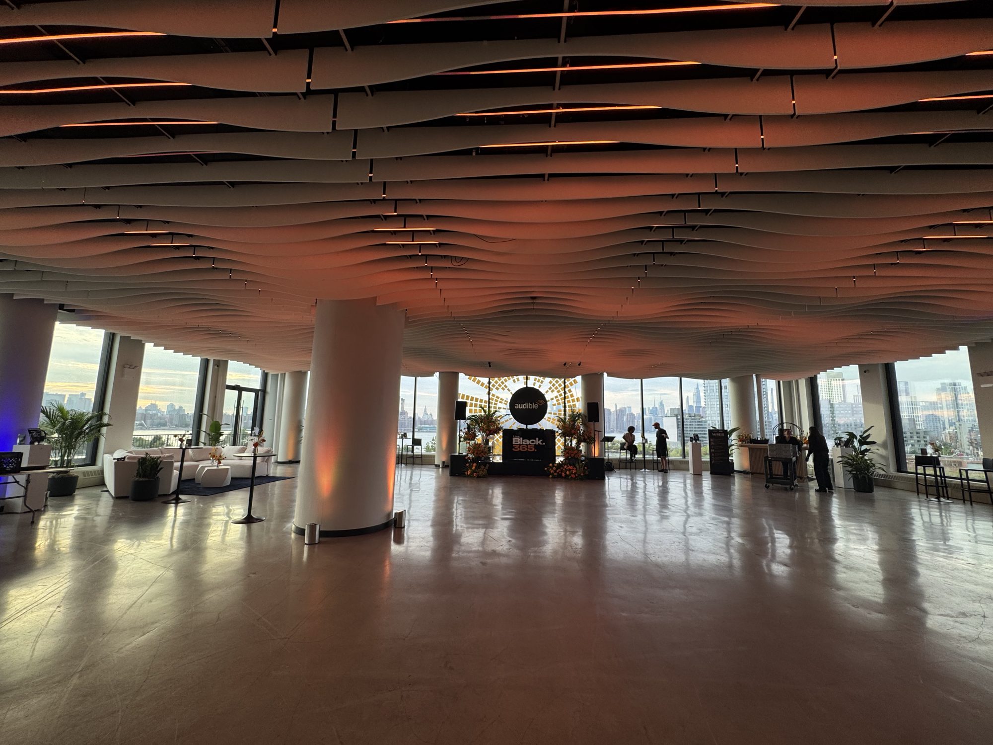 Wide view of VESPER set for a 200-guest creator networking evening, with a stage, florals and the Manhattan skyline