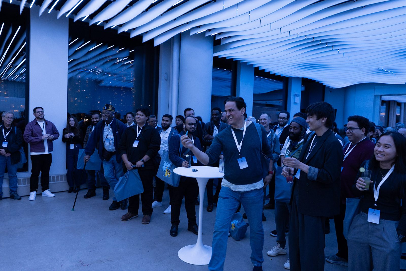 A crowd of guests with lanyards cheering under the wave ceiling at VESPER during a Microsoft product night